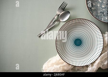 Top view, Trendy ceramic porcelain plates with fork and spoon on modern grey table background. Stock Photo