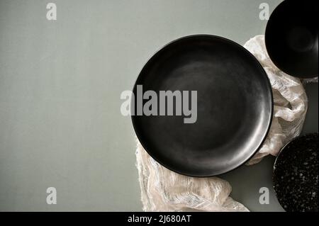 Modern black ceramic plates with white tablecloth and copy space on grey table background. top view Stock Photo