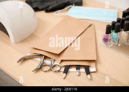 Paper bags with clean manicure instruments on wooden table, closeup Stock Photo