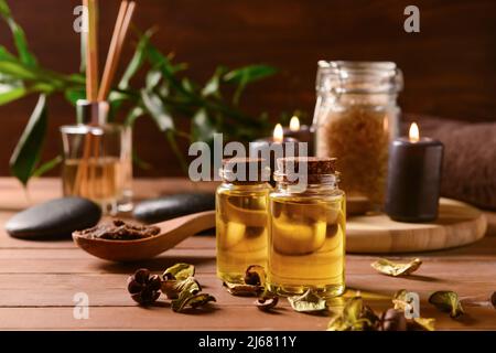 Bottles of essential oil and dried rose petals on wooden table Stock Photo