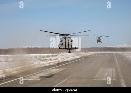 Alaska Army National Guardsmen with the 2-211th General Support Aviation Battalion prepare to land UH-60L Black Hawk and CH-47 Chinook helicopters in McGrath, Alaska, April 11, 2022. After refueling at the local airport, the Guardsmen will continue their route from Joint Base Elmendorf-Richardson to Nome where the UH-60L Black Hawk helicopters will remain for Golf Company, Detachment 1, 2-211th GSAB to conduct annual training and aide in River Watch if needed this spring. Should there be significant flooding or other emergency in the vicinity, the Black Hawk helicopters will provide support as Stock Photo