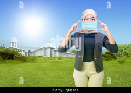 Asian Muslim woman in a headscarf and wearing a face mask while activity an outdoor Stock Photo