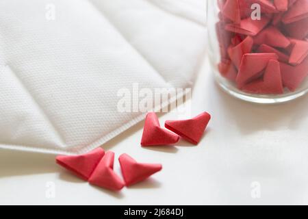 White facemask, Pink and red three-dimensional origami artwork and transparent glass jar - stock photo Stock Photo