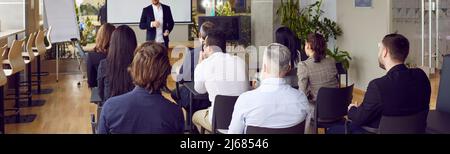 Rear view of people on business training listening to male coach who lectures and trains staff. Stock Photo