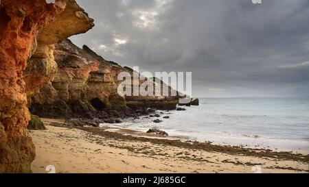 High cliffs towering over beach and sea on a cloudy day, Pintadinho ocean landscape, Algarve, Portugal, Europe Stock Photo