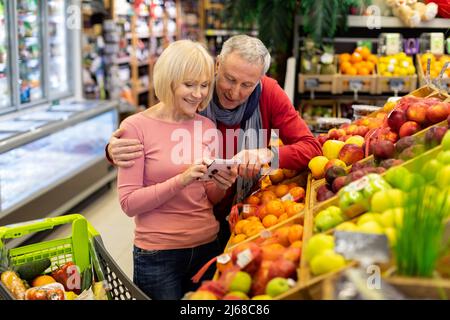 Smiling customers senior couple walking in supermarket Stock Photo