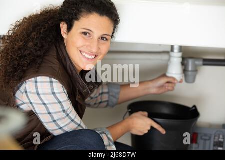 female plumber fixing sink in kitchen Stock Photo