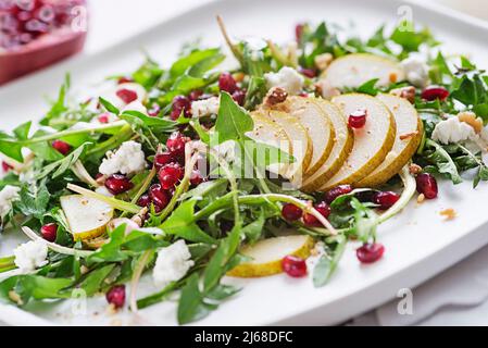 Healthy dandelion salad with pear fruit, pomegranate and fresh cheese close up Stock Photo
