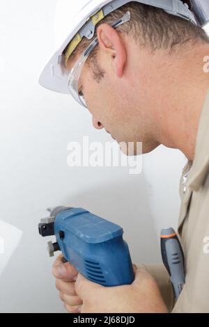 builder drills a hole in the wall Stock Photo