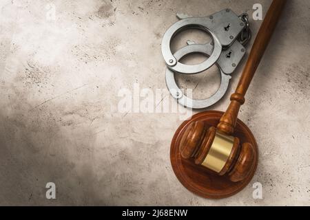 Wooden gavel of the judge and handcuffs on the right side on an abstract background with copy space, top view Stock Photo