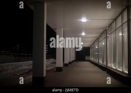 Building is in dark. View of pillars. Windows in row. Perspective of corridor. Stock Photo
