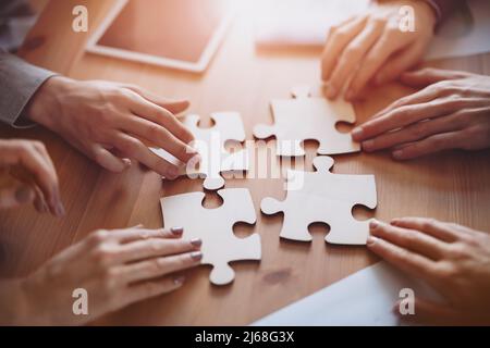 Buisnesswomen and buisnessmen working together while putting together puzzles. Stock Photo