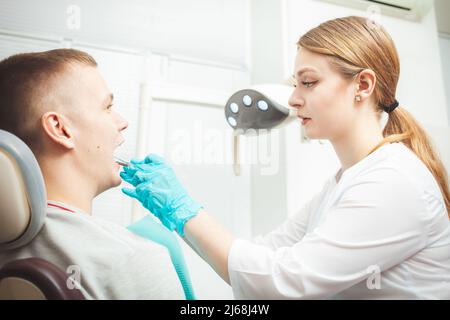 European female dentist doctor treats patient, examines mouth and teeth. Professional service, friendly, smiling, happy and satisfied, calm. private c Stock Photo
