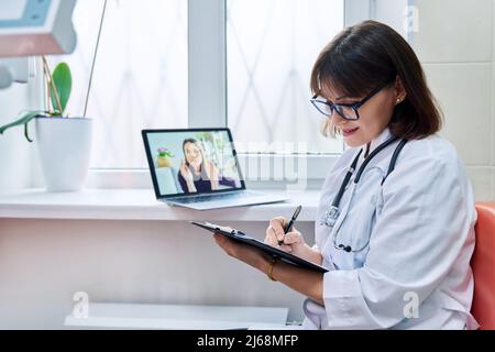 General practitioner doctor talking on videoconference with female patient Stock Photo