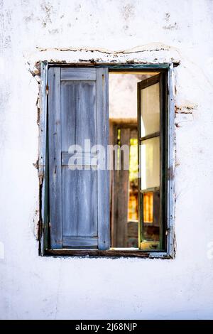 Antique window on a white old wall and gold light inside. Stock Photo