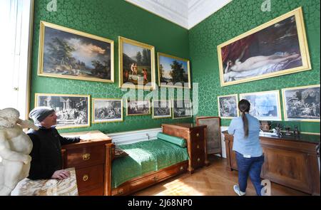 Bitterfeld Wolfen, Germany. 28th Apr, 2022. 28 April 2022, Saxony-Anhalt, Bitterfeld-Wolfen: Visitors stand in the bedroom of Prince Leopold III Friedrich Franz of Anhalt-Dessau during a guided tour of Wörlitz Palace. The palace was built from 1769-1773 by order of Prince Leopold III Friedrich Franz of Anhalt Dessau for him and his wife Luise Princess of Brandenburg-Schwedt by master builder Friedrich Wilhelm von Erdmannsdorff. In the last 20 years, the founding building of German classicism on the European mainland has been extensively restored. Located in Wörlitz, the palace in the Dessau-Wö Stock Photo