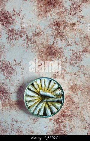 Overhead view of a large round sardine tin on a weathered and painted textured background. Food storage and fish. Stock Photo