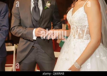 Wedding, the groom's hand places the ring on the bride's hand. Stock Photo