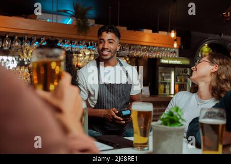 diverse friends out for dinner paying bill with card machine  Stock Photo