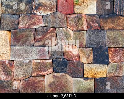 Multicolored stones of irregular shapes, arranged in an intricate mosaic design across a wall or floor Stock Photo