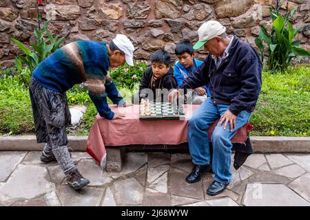 Two Men Playing Chess Watched By Local Children, Pisac, The Sacred Valley, Calca Province, Peru. Stock Photo