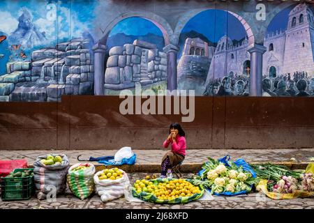 A Child Selling Fruit and Vegetables Eats Lunch At An Outdoor Fruit and Vegetable Street Market, Cusco, Cusco Province, Peru. Stock Photo