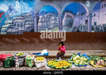 A Child Selling Fruit and Vegetables Eats Lunch At An Outdoor Fruit and Vegetable Street Market, Cusco, Cusco Province, Peru. Stock Photo