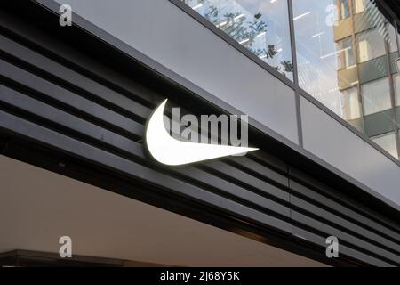 Nike Swoosh logo on a facade of a store in the capital of Germany. Illuminated company brand sign as advertising on a building. Modern architecture Stock Photo