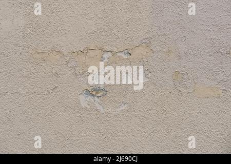 Weathered old wall plaster with damaged surface. Beige brown wall stone structure with a visible mesh. Abstract vintage texture of a house. Stock Photo