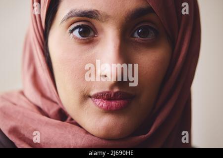 Portrait of young Muslim woman wearing hijab looking towards camera with pensive expression Stock Photo