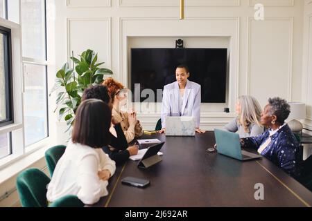 Portrait of multiracial LGBTQ mid adult businesswoman listening to female colleagues and smiling in meeting Stock Photo