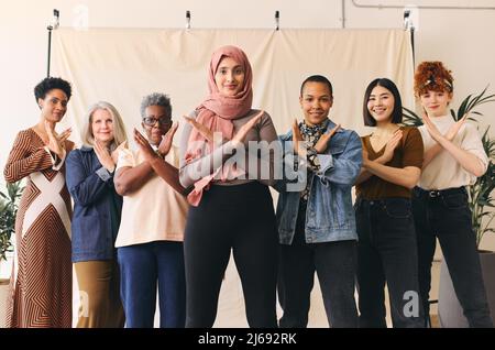 Middle Eastern woman wearing hajib gesturing Break The Bias in support of International Women's Day with female friends Stock Photo