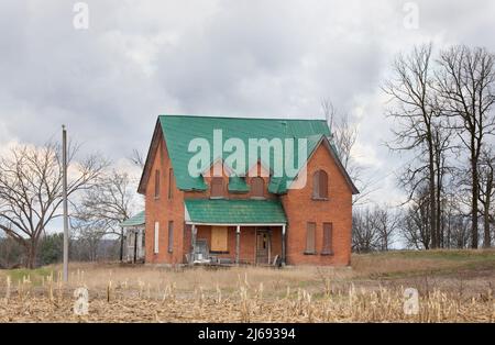 An old abandoned farmhouse in spring on a farm yard in rural Canada Stock Photo