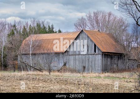 An old wooden barn sits idle on a country road in Ontario, Canada Stock Photo