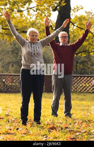 middle aged Caucasian couple doing gymnastics in park autumn healthy lifestyle concept full shot . High quality photo Stock Photo