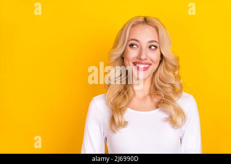 Photo of pretty dreamy lady dressed white shirt smiling looking empty space isolated yellow color background Stock Photo