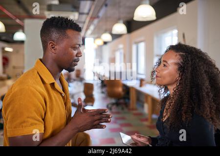 Two colleagues have a discussion in an open plan creative office Stock Photo