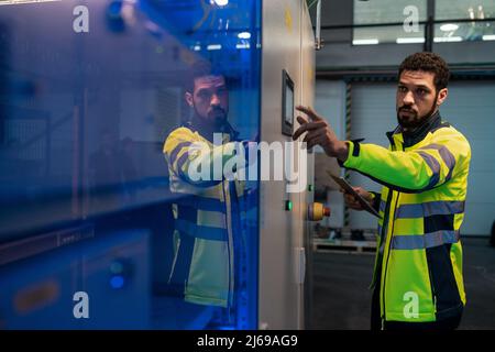 Young industrial worker operating cnc machine at metal machining industry Stock Photo