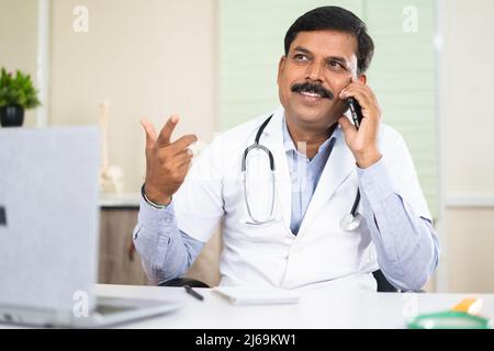 happy smiling doctor busy talking with patient on mobile phone call - concept of communication, support and consultation Stock Photo