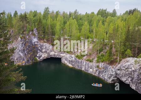 Karelian landscape with tourists in boat sailing the former marble quarry filled with groundwater. Ruskeala, Russia Stock Photo