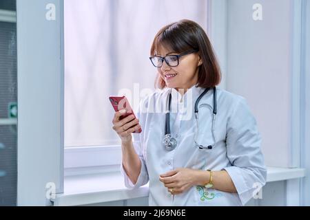 Female doctor with stethoscope with smartphone in her hands in hospital. Stock Photo