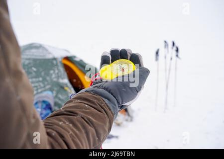 Big beautiful yellow compass in hand. A traveler holds a gloved compass at the north pole in winter. Compass on a winter expedition Stock Photo