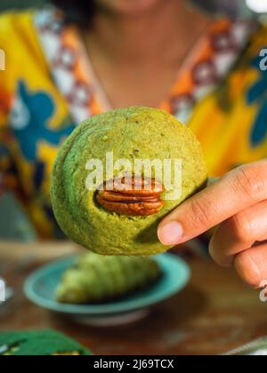 Close-up shot woman's hand holding pecan cookie. Stock Photo