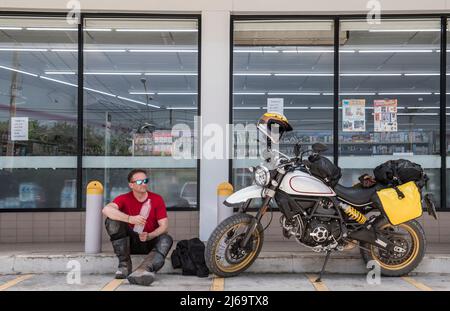 Man taking a break on motorcycle ride in Thailand Stock Photo