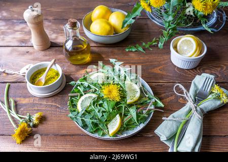 Dandelion salad with dip made with olive oil, lemon juice and spices on brown wooden table. Stock Photo