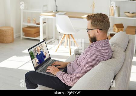 Business man sitting at home on weekend watching business training or online webinar on laptop. Stock Photo