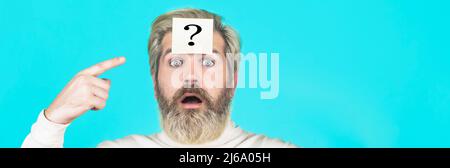 Paper notes with question marks. Thinking man with question mark on blue background. Man with question mark on forehead looking up Stock Photo