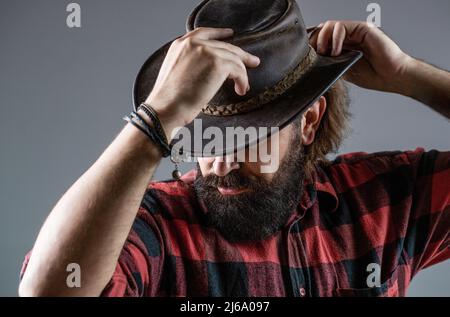 Man unshaven cowboys. American cowboy. Leather Cowboy Hat. Portrait of young man wearing cowboy hat. Cowboys in hat. Handsome bearded macho Stock Photo