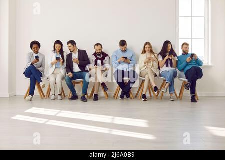 Diverse candidates in line using smartphones Stock Photo