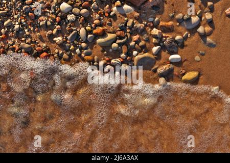 Directly Above Flatlay of Gentle Waves Lapping Sand and Pebble Beach with Pristine Clear Cool Water  Stock Photo